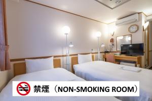 a hotel room with two beds and a tv at Hotel Endear Gifu in Gifu