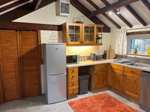 a kitchen with a white refrigerator and wooden cabinets at Twattleton Cottage Kilburn Yorkshire - Beautiful views in York