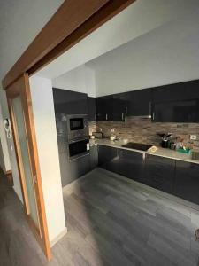 a large kitchen with black cabinets and appliances at Spacious House 3 Rooms in Barreiro