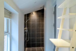 ein Bad mit einer Dusche mit schwarzen Fliesen in der Unterkunft Brooklyn Penthouse in Kopenhagen