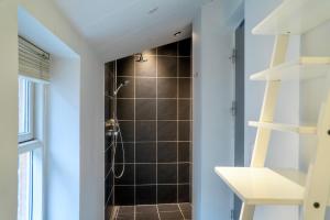 baño con ducha de azulejos negros en Brooklyn Penthouse en Copenhague