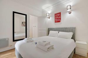 ein Schlafzimmer mit einem weißen Bett und Handtüchern darauf in der Unterkunft Cosy 2P flat Parc des Princes Exelmans in Paris