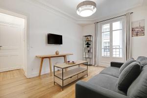 ein Wohnzimmer mit einem Sofa und einem Tisch in der Unterkunft Cosy 2P flat Parc des Princes Exelmans in Paris