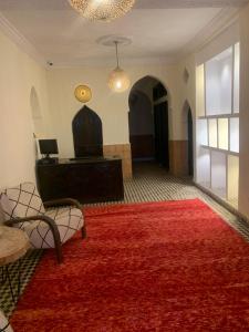 タルーダントにあるHotel Riad Taroudantの赤い敷物のあるリビングルーム、テーブル付きの部屋