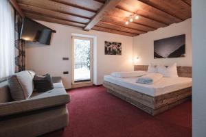 a bedroom with two beds and a couch and a television at Garni Petter in Kappl