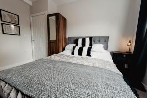 1 dormitorio con 1 cama grande con almohadas blancas y negras en K Suites - Station Road, en Hinckley