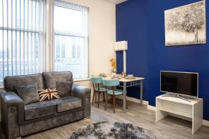 een woonkamer met een bank, een tv en een tafel bij Station Apartment - 3 bedroom, five minutes from Harrogate Convention Centre in Harrogate