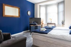 1 dormitorio con paredes azules, 1 cama y 1 silla en Station Apartment - 3 bedroom, five minutes from Harrogate Convention Centre en Harrogate