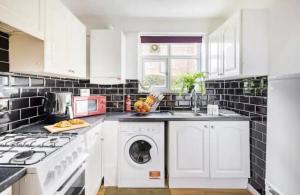 a kitchen with white cabinets and a washer and dryer at K Suites - Harboro Grove in Sale