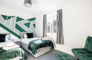 a bedroom with two beds and a green chair at K Suites - Harboro Grove in Sale