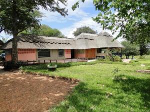 a house with a thatched roof in a yard at Hippo Paradise Lodge and Campsites in Kariba