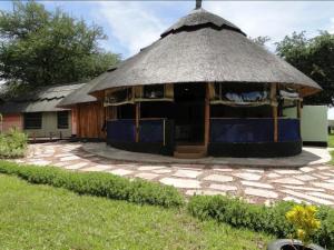 a hut with a thatched roof in a yard at Hippo Paradise Lodge and Campsites in Kariba