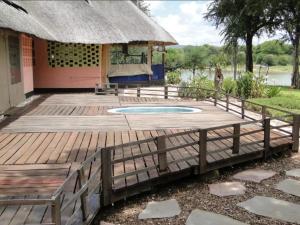 una terraza de madera frente a un edificio con una cabaña en Hippo Paradise Lodge and Campsites, en Kariba