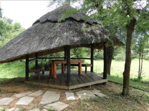 Hippo Paradise Lodge and Campsites في Kariba: شرفة مع طاولة وسقف عشبي
