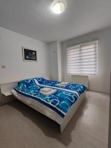 ein Schlafzimmer mit einem Bett mit einer blauen Decke in der Unterkunft Konak in Kragujevac