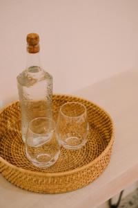 three wine glasses and a bottle on a wicker tray at BIG WAVES BOUTIQUE HOTEL SIARGAO in General Luna