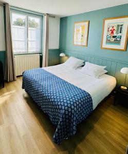 - une chambre avec un grand lit et un mur bleu dans l'établissement Hotel L'Océan, au Bois-Plage-en-Ré