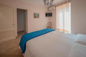 a bedroom with a large white bed with a blue blanket at Uno Scorcio sulla Rocca by Wonderful Italy in Cefalù