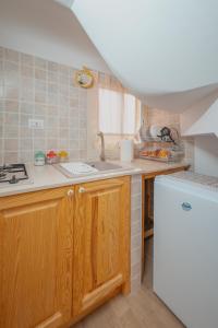 a kitchen with wooden cabinets and a white refrigerator at Uno Scorcio sulla Rocca by Wonderful Italy in Cefalù