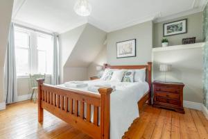 um quarto com uma cama de madeira e piso de madeira em Braeside - 4 Beds - Sleeps 8 - Garden em St. Andrews