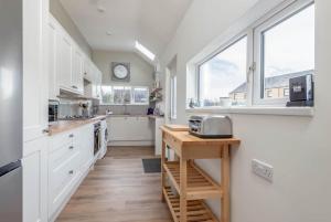 a kitchen with white cabinets and a clock on the wall at Braeside - 4 Beds - Sleeps 8 - Garden in St Andrews