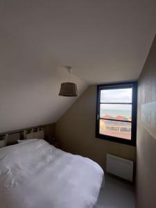 une chambre avec un lit blanc et une fenêtre dans l'établissement Appartement à la Naturelle, à Wimereux