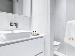 a white bathroom with a sink and a toilet at Limassol Del Mar in Limassol