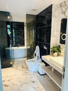a bathroom with a toilet and a glass shower at DELUXE VILLA 4 phòng ngủ 5 giường lớn in Hue