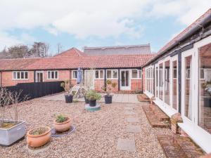 a courtyard of a house with potted plants at Avocet Cottage in Saxmundham