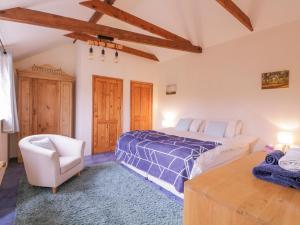 a large bedroom with a bed and a chair at Avocet Cottage in Saxmundham