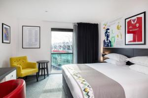 una camera d'albergo con un letto, una sedia e una finestra di Hotel Football, Old Trafford, a Tribute Portfolio Hotel a Manchester