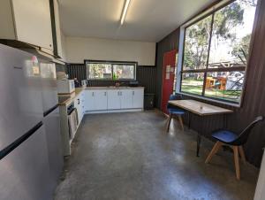 uma cozinha com armários brancos e uma mesa e cadeiras em Tiny House 14B at Grampians Edge em Dadswells Bridge