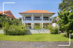 een wit huis met een balkon en een tuin bij Villa Resort Da Nang Abogo in Da Nang