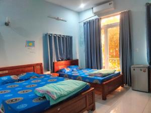 2 łóżka pojedyncze w pokoju z oknem w obiekcie Công ty TNHH Khách sạn Lê Phan w mieście Cu Chi
