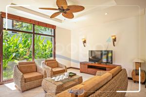 een woonkamer met een bank en stoelen en een tv bij Villa Resort Da Nang Abogo in Da Nang