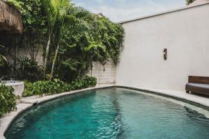 a swimming pool with a bench next to a building at Sini Vie Villa Seminyak by Ini Vie Hospitality in Seminyak