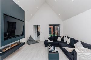 a living room with a black couch and a flat screen tv at The Glass House in Dorchester on Thames