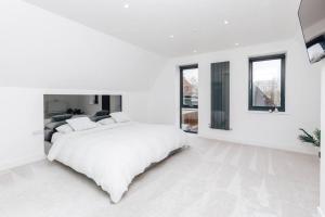 a white bedroom with a large bed and windows at The Glass House in Dorchester on Thames
