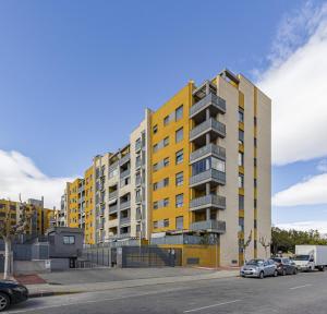 un edificio amarillo con coches estacionados en un estacionamiento en Parque Norte, en Cabezo de Torres