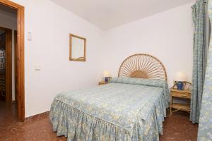 a bedroom with a bed with a blue bedspread at El Paseo del Faro in Chipiona