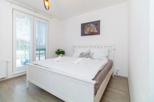 een witte slaapkamer met een wit bed en een raam bij Three bedroom apartment with teracce and garden in Moravská Ostrava