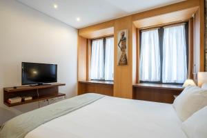 a bedroom with a bed and a tv and windows at Reis de Gaia in Vila Nova de Gaia