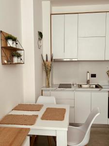 a kitchen with white cabinets and a table and chairs at Foleza Studio Apartament-Shengjin in Margjonaj
