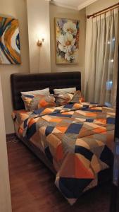 a bed with a colorful comforter in a bedroom at Cozy Apartment Asatti Agate Yellow Vanya Park in Pagedangan