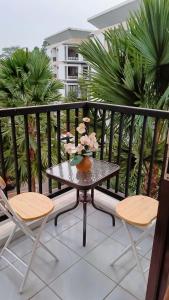 een tafel met bloemen op een balkon met stoelen bij Cozy Apartment Asatti Agate Yellow Vanya Park in Pagedangan