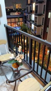 een vaas met bloemen op een glazen tafel op een balkon bij Cozy Apartment Asatti Agate Yellow Vanya Park in Pagedangan