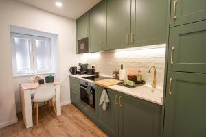 a kitchen with green cabinets and a sink at MAM HEAT River Nest - Darque Village Centre in Viana do Castelo