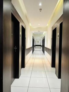 pasillo con puertas negras y suelo de baldosa blanca en Hotel Shagun Rooms & Banquet, Surat, en Surat