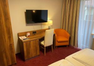 a hotel room with a desk with a television and a chair at Morada Hotel Bad Wörishofen in Bad Wörishofen