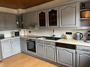 a kitchen with white cabinets and a sink at Eifel Ferienwohnung Thiel in Oberstadtfeld